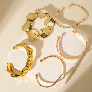 Detail view of five-piece gold bangle set with hammered texture and polished finish on stones