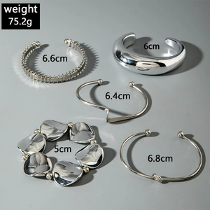 Macro view of 5-piece silver-tone geometric knot bangles with weights and sizes