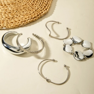 Set of five silver geometric bracelets featuring smooth, wavy, and beaded metal designs