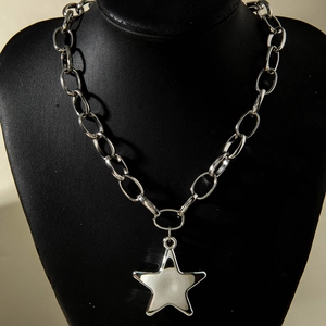Macro shot of silver chunky link chain necklace featuring a large polished star pendant