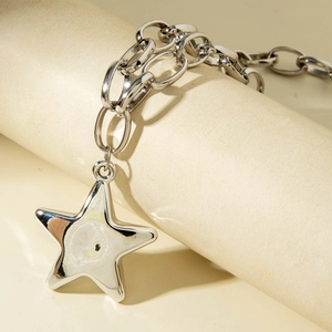 Macro shot of silver oversized star pendant and chunky oval link chain on a prop