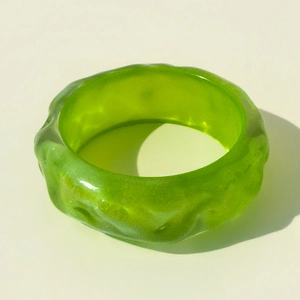 Detail showing the wavy texture and glitter finish of the translucent green resin bangle