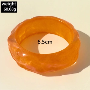 Close-up of orange translucent resin bangle showing wave texture and 6.5cm inner diameter