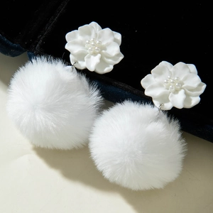 Detailed macro view of white flower earrings with fluffy pom-poms and pearl accents