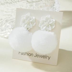 Detail showing white resin flower stud with a soft faux fur pom-pom winter earring