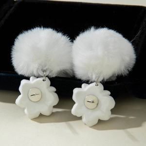Detail of white faux fur ball earrings with resin flower charms on black velvet