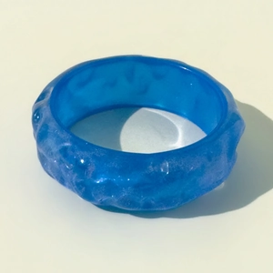 Detail of blue resin bangle featuring irregular water ripple texture and glitter finish