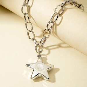 Silver chunky chain necklace with large pentagram star pendant on a beige jewelry display