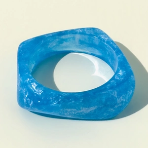 Detalle de anillo de resina azul real translúcido con textura jaspeada y forma geométrica
