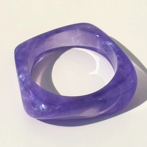 Detalle macro de la pulsera de resina púrpura translúcida con forma geométrica cuadrada