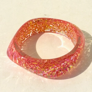 Detail of colorful glitter resin bracelet with pink and orange gradient and sparkles