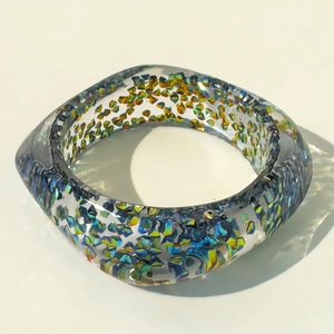 Close-up of resin bangle with colorful iridescent glitter flakes and square geometry