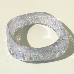Macro shot of wide resin bangle with colorful glitter and sparkling light reflections