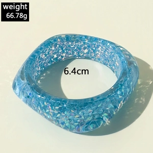 Detail view of wide blue translucent resin bangle with sparkling glitter and 6.4cm diameter