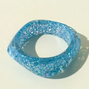 Detail of teal resin bangle with embedded sparkling iridescent glitter sequins