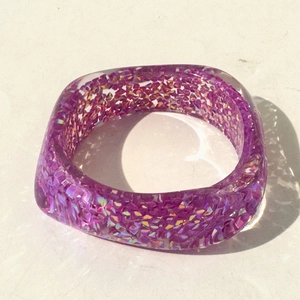 Macro shot of thick purple resin bangle with sparkling glitter and laser sequins