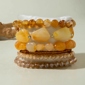 Detail of bohemian multilayer beaded bracelets with amber crystals on a display pillow