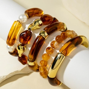 Detailed macro view of bohemian amber resin beads and gold-tone layered bracelets