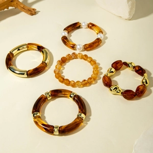 Detail of five bohemian resin bead bracelets with amber textures and gold accents