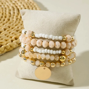 Dettaglio set bracciali bohémien su cuscino portagioie con ciondolo a moneta d'oro
