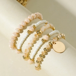 Dettaglio del set di 5 braccialetti elastici con perline color champagne e bianco