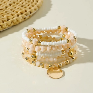 Dettaglio di bracciali multistrato boho con perline di resina e ciondoli dorati