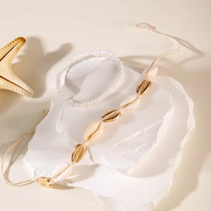 Detalle de set de joyas playeras con cuentas blancas y conchas marinas en piedras