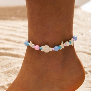 Detalle de tobilleras de cuentas con colgantes de estrella y tortuga de mar en la playa