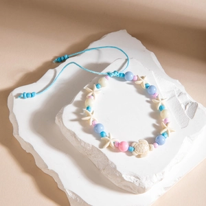 Detalle de tobillera de cuentas azules con dijes de estrella de mar y tortuga marina