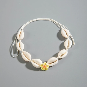 Detalle del collar de conchas hecho a mano con cauris blancos y una flor de frangipani