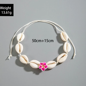 Detalle de un collar de conchas blancas con una flor de frangipani púrpura de moda