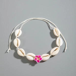 Detalle del collar de conchas con cauríes y flor de frangipani amarilla para la playa