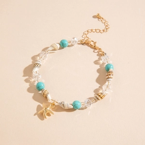 Detalle de cuentas de colores, concha y dije de estrella de mar dorada en la tobillera