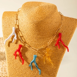 Gros plan du collier à maillons dorés avec pendentifs corail colorés sur un mannequin