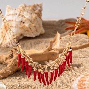 Détail du collier à maillons dorés orné de pendentifs en forme de piment rouge corail