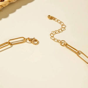Détail du fermoir mousqueton doré et chaîne trombone ajustable avec perle métallique