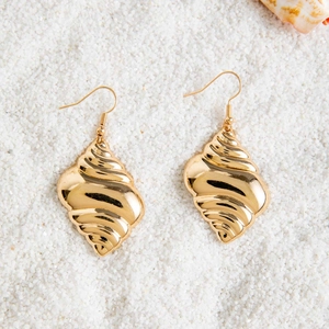 Close-up of golden shell-shaped earrings on white beach sand with nautical textures