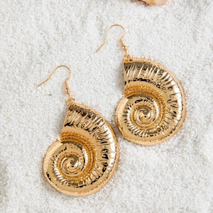 Detailed view of golden starfish seashell drop earrings on white beach sand background