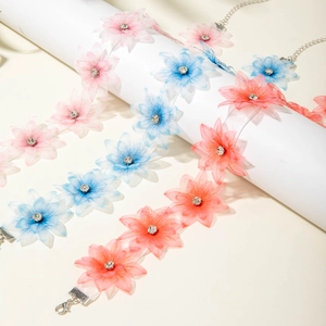 Detail of bohemian fabric flower necklaces with rhinestone centers in pink, blue, and coral