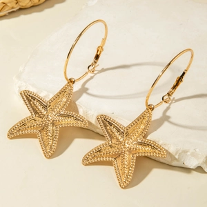 Macro detail of golden starfish pendant with textured relief on gold hoop earrings