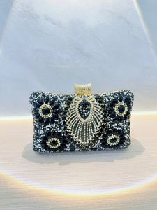 Dettaglio di una pochette da sera nera di lusso con cristalli floreali e cornice in metallo dorato