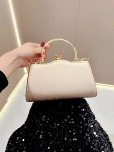 Close-up of cream evening clutch bag with elegant gold metal handle and velvet texture