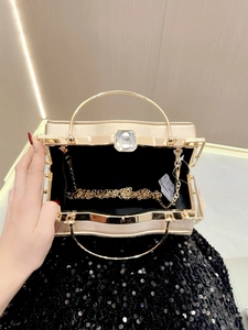 Champagne gold evening clutch with crystal buckle and round metal handle shown held by hand