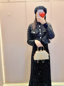 Detailed view of a gold rhinestone handbag paired with a black sequin two-piece evening set