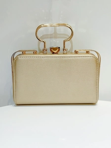 Detail of champagne gold evening clutch with hollow metal handle and gemstone clasp