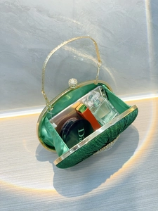 Detail view of green pleated evening clutch with gold handle and rhinestone lock