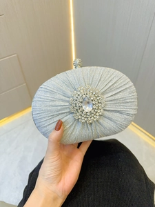 Close-up of silver pleated evening bag featuring a crystal rhinestone floral brooch