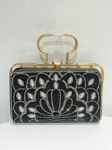 Close-up of black rhinestone evening bag with elegant pearl flower pattern and gold ring handle