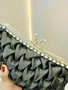 Detail of elegant black pleated satin evening clutch with sparkling rhinestone trim