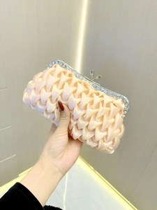 Detail of champagne satin evening clutch featuring pleated texture and rhinestone trim